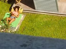 Чувак с окна снимает на камеру одну классную негритянку, которая лежит во дворе и загорает